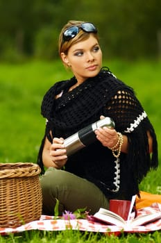 Young business woman with cup during picnic on green meadows outdoors