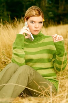 Young business woman using cell phone on golden meadow at mountains outdoors