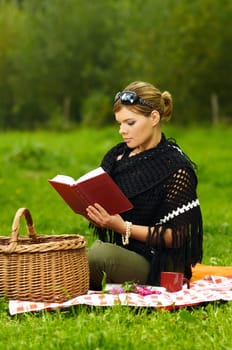 Young business woman with book during picnic on green meadows outdoors