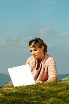Young business woman relaxing, working on laptop computer on meadow