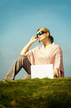 Young business woman relaxing, working on laptop computer on meadow