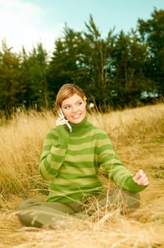 Young business woman using cell phone on golden meadow at mountains outdoors