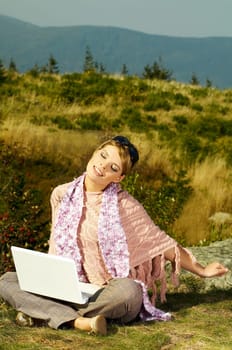 Young business woman relaxing, working on laptop computer on meadow