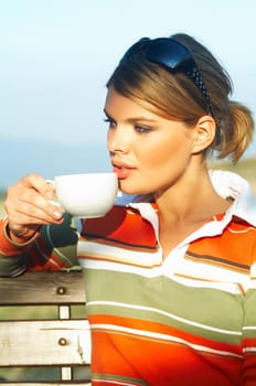 Young woman relaxing, drinking coffee at mouintain outdoors
