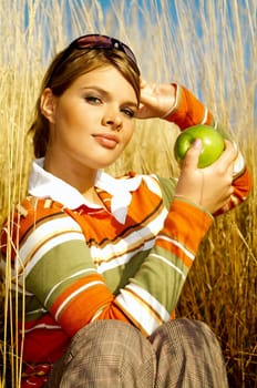Young business woman relaxing on meadow, holding green fresh apple