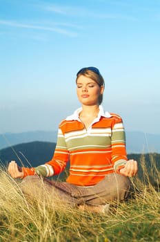 Young beautiful woman relaxing on meadow at mouintain outdoors