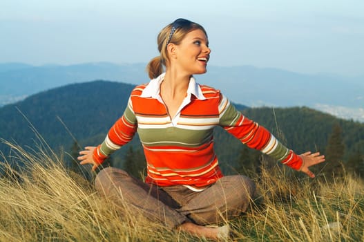 Young beautiful woman relaxing on meadow at mouintain outdoors