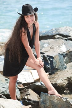 Young woman in black hat near the ocean