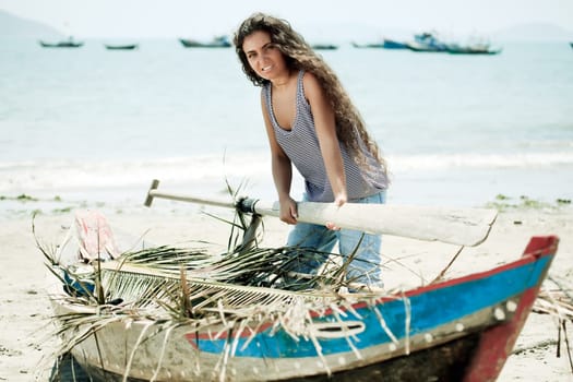 Young beautiful fisherwoman with boat on the beach