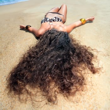 Young beautiful woman is sunbathing on the sand