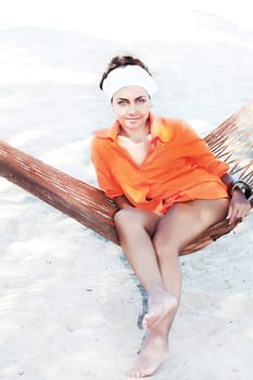 Young woman relaxing in hammock on the sandy beach