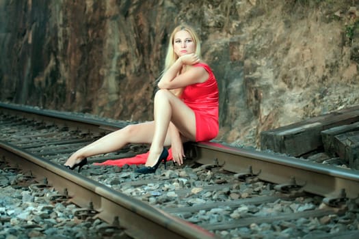 Young beautiful woman is sitting on train track