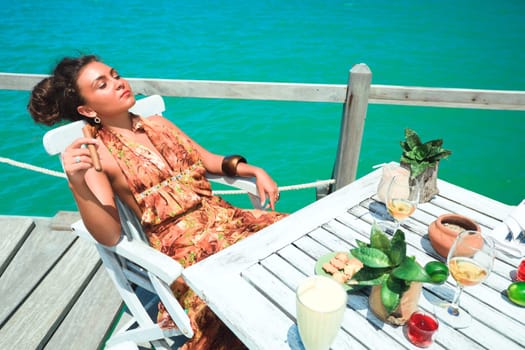 Young woman with cigar has a dinner on the beach