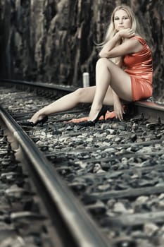 Young beautiful woman sitting on train track