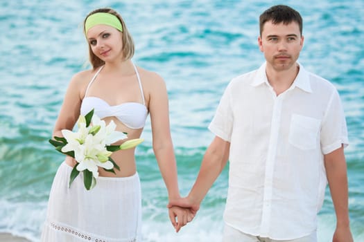 Romantic couple near the ocean with flowers