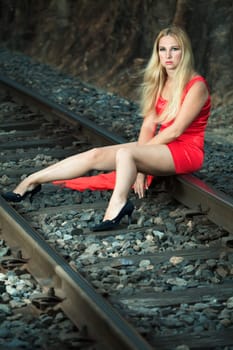 Young beautiful woman sitting on train track