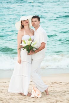 Romantic couple near the ocean with flowers