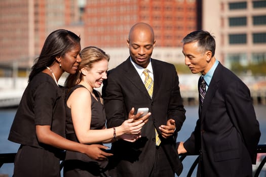 A group of business people crowded around a cell phone