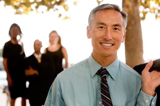 An asian looking business man with colleagues in the background