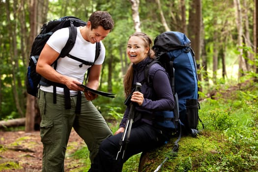 A couple with smiles looking at a map in the forest