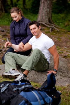 A woman applying an arm bandage on a male camper - focus on male face