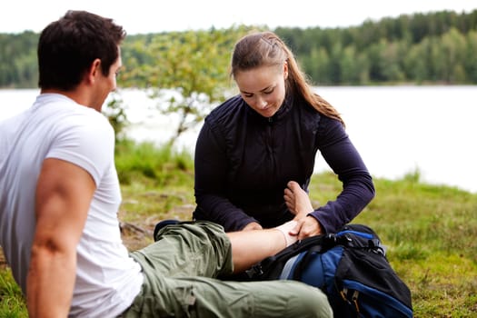 A woman applying an ankle bandage on a male camper