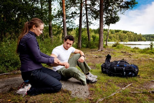 A woman applying an arm bandage on a male camper