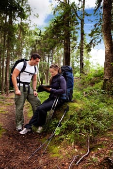 A couple backpack camping in the forest looking at a map