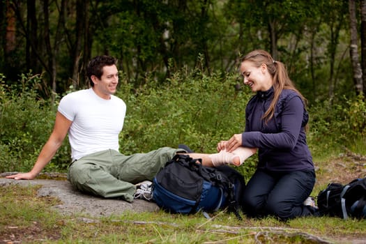 A couple camping and putting on a leg bandage
