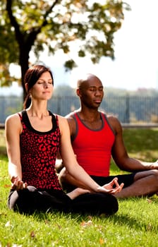 Two people meditating in a city park on a sunny day