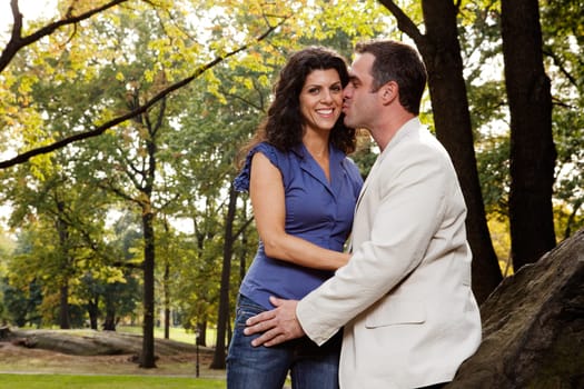 A man kissing his girlfriend / wife in the park