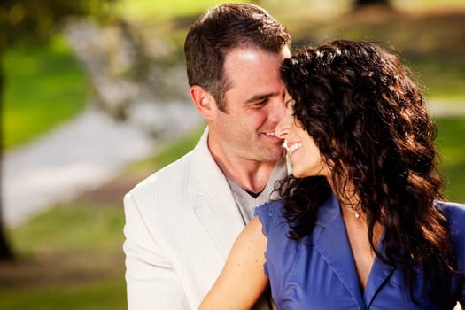 A happy couple in the park sharing a hug and kiss