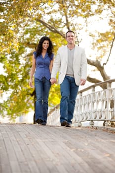 A couple walking on a bridge in a park