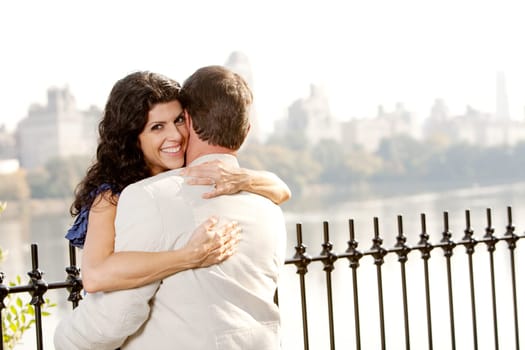 A woman hugging a man and looking at the camera with a smile