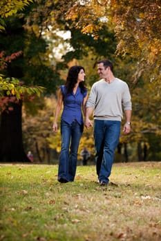 A happy couple walking in the park on grass