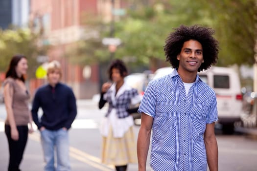 Four people on city street with young male as focus. Horizontally framed shot.