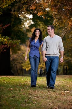 A happy couple walking in the park on grass