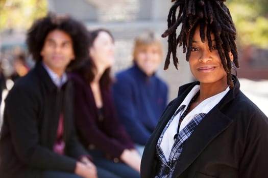 Group of four people of different ethnicities with one woman as focus of image. Horizontally framed shot.
