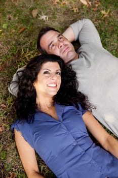 A couple day dreaming while laying on grass