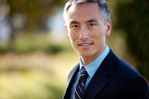 Middle aged male businessman in suit and tie standing outside. Horizontally framed shot.