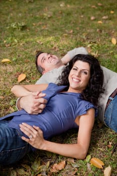 A happy couple relxing laying in the grass - sharp focus on the woman