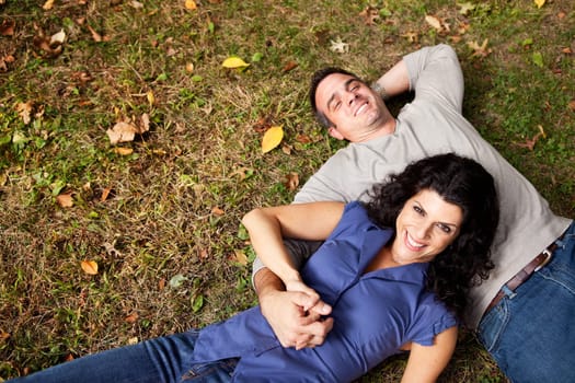 A happy couple daydreaming in a park on grass - sharp focus on woman