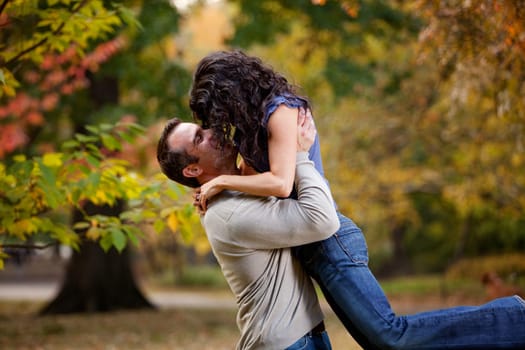 A man giving a woman a big hug in a park