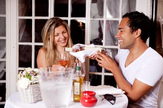 A happy couple sharing a bottle of wine in an outdoor cafe in Europe