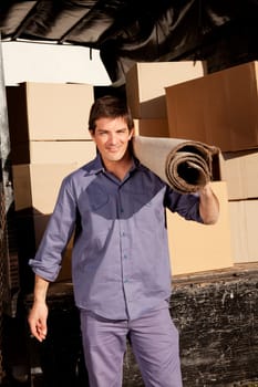 A portrait of a professional mover with a carpet and boxes in the background