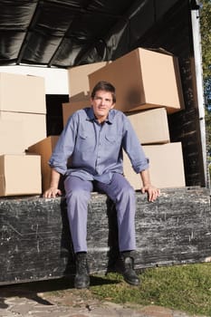 Thoughtful man sitting in the truck with pile of boxes behind him