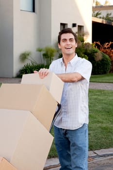 A happy male looking at the camera pushing a dolly with moving boxes