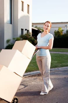 A woman with a stack of cardboard boxes on a trolly