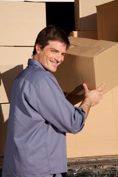 A portrait of a happy mover, moving cardboard boxes