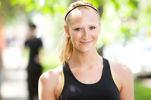 Close-up of a pretty woman in sports wear with friend in the background
